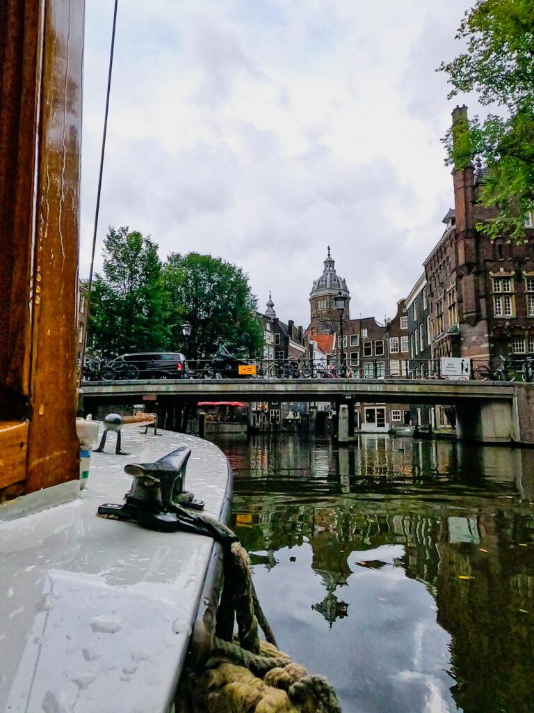 Amsterdam canal boat tour showcasing Dutch architecture, serene reflections, and lush greenery.