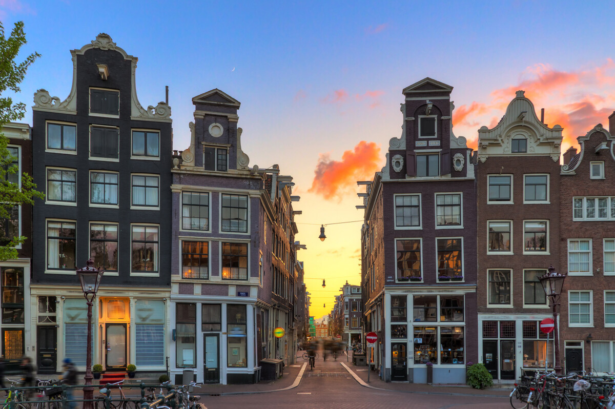Shops in Amsterdam along historic canal houses at sunset.