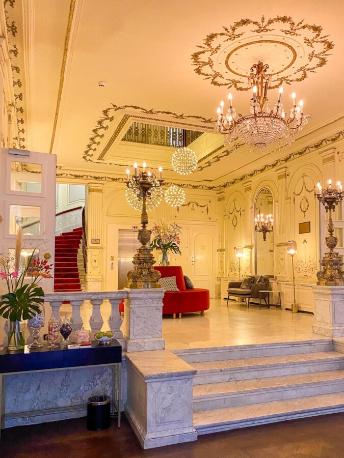 Luxurious Tivoli Doelen Hotel lobby in Amsterdam with grand staircase and ornate chandeliers