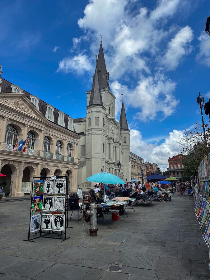 Art vendors at Jackson Square with St. Louis Cathedral under blue sky, New Orleans