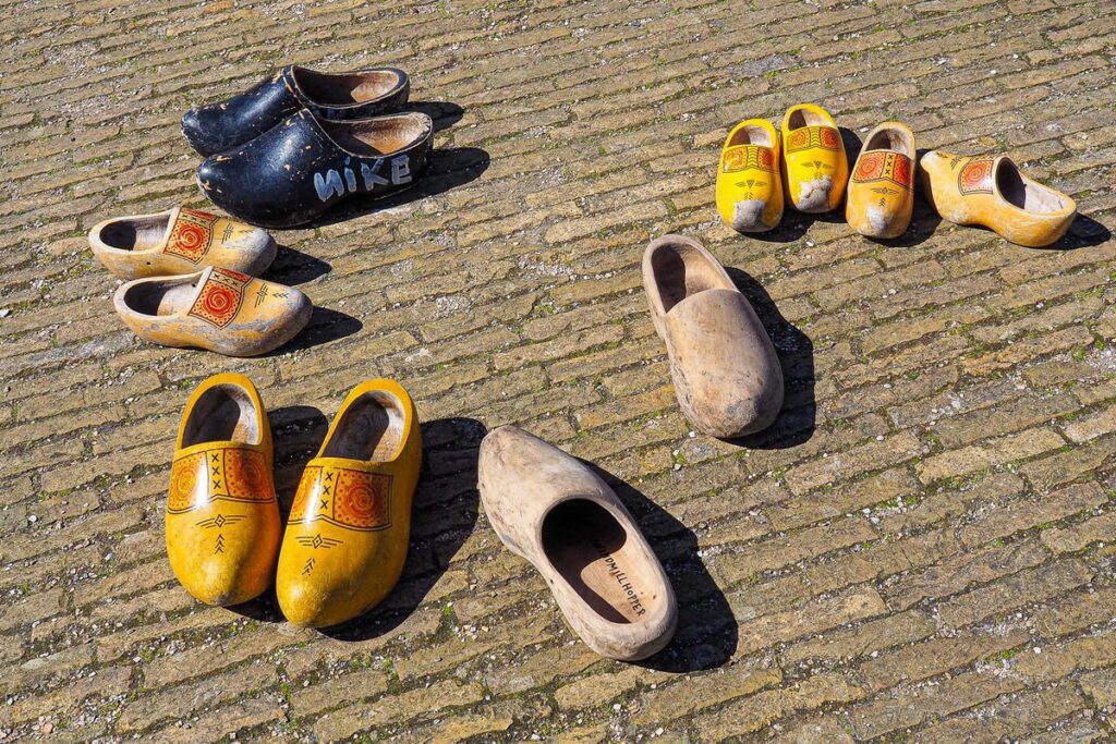 Assorted Dutch wooden clogs, or klompen, with iconic yellow folk patterns on cobblestone street