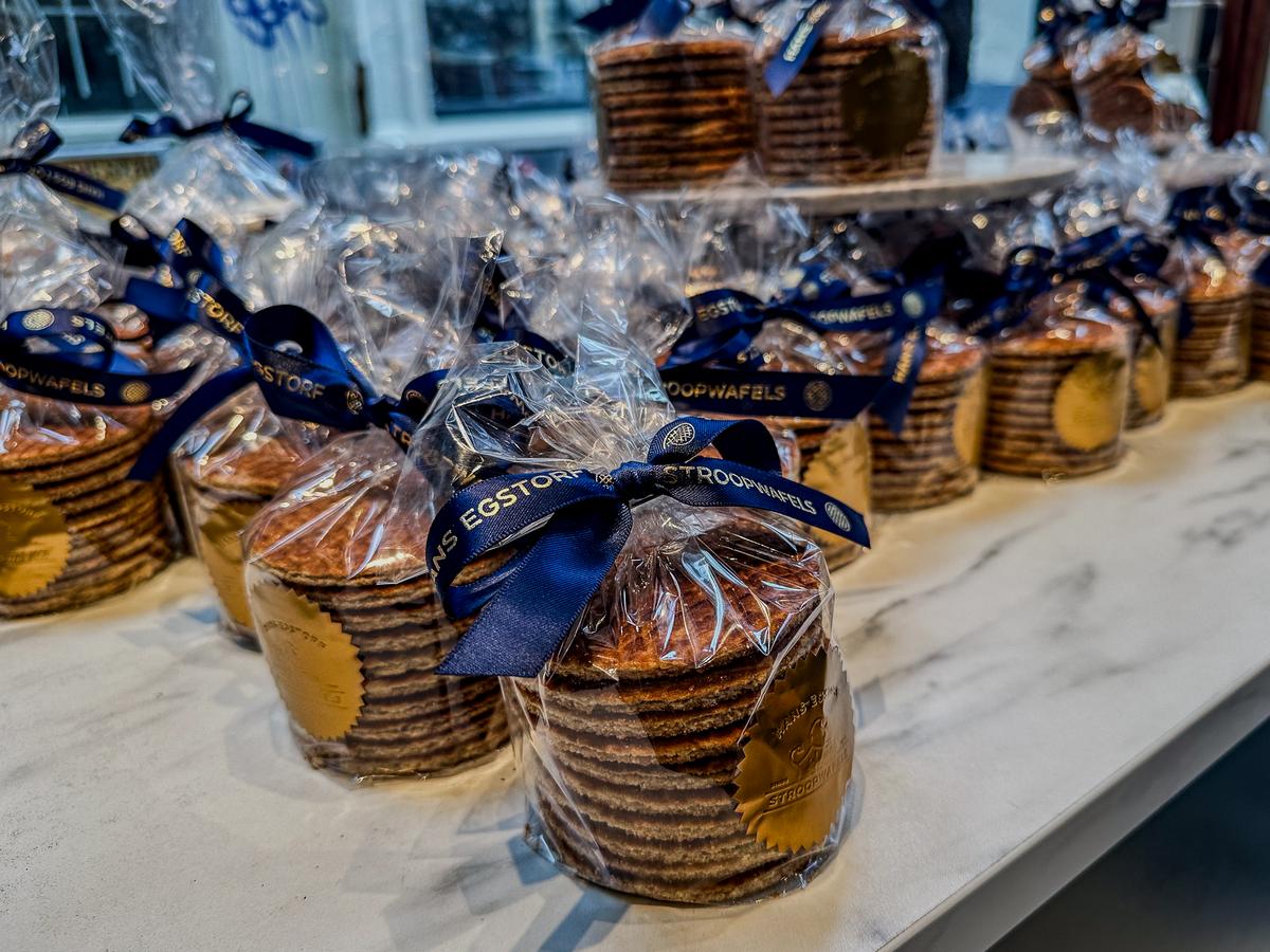 Stacks of authentic Dutch stroopwafels with Hans Egstorf branding, packaged with a royal blue ribbon, on display in Amsterdam.
