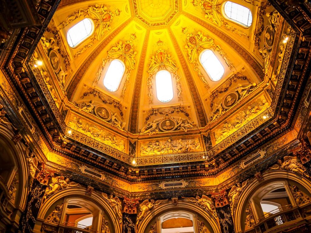 Baroque interior of Kunsthistorisches Museum in Vienna, Austria - intricate ceiling, golden stucco, classical sculptures in vibrant colors.