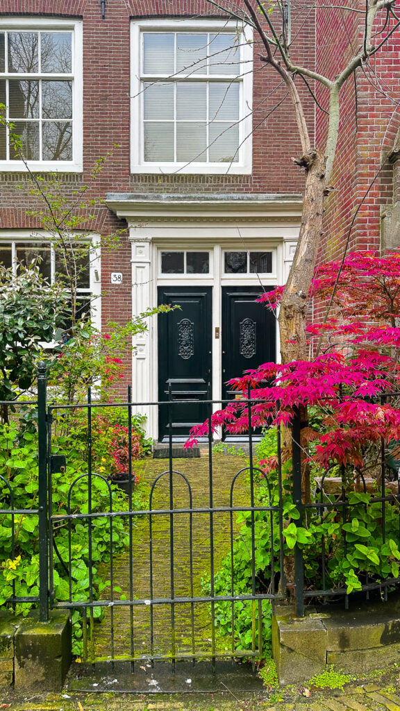 Traditional Dutch house with black doors and greenery in Begijnhof, Amsterdam.