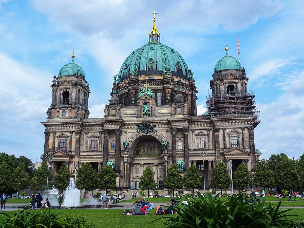 Visitors at Berlin Cathedral park with scaffolding on dome