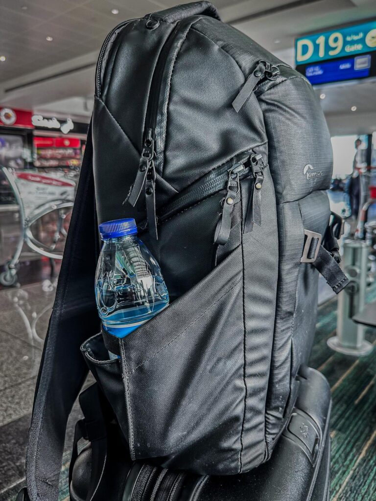 Black Lowepro Freeline camera backpack and Beis luggage at airport terminal gate D19