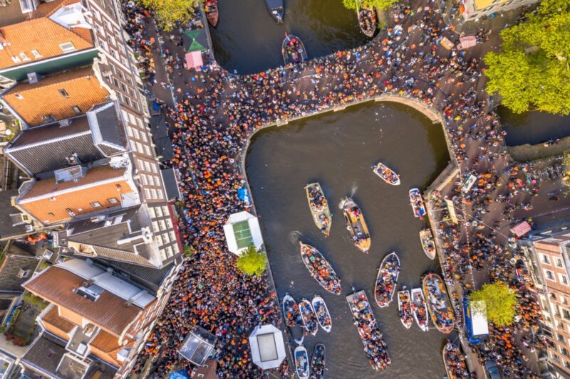 Canal boat parade on Koningsdag Kings day festivities in Amsterdam. Birthday of the king. Seen from helicopter.