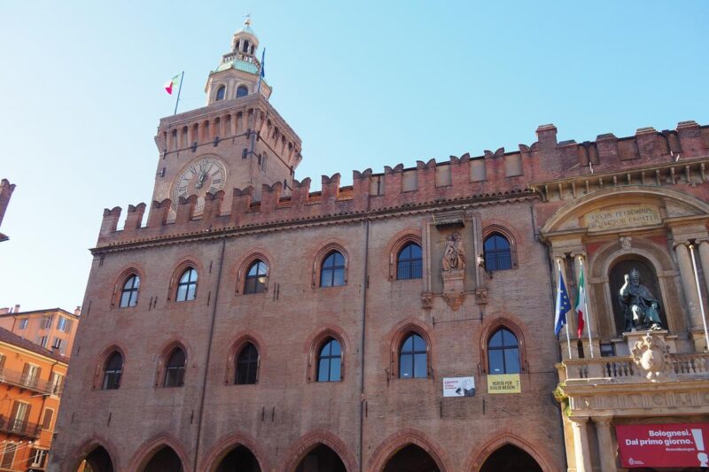 Historic Bologna City Hall with grand clock tower and Italian flag
