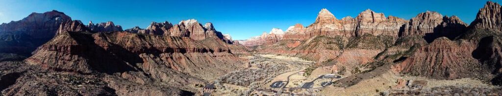 Panoramic view of Zion National Park with iconic red sandstone cliffs and clear blue sky.