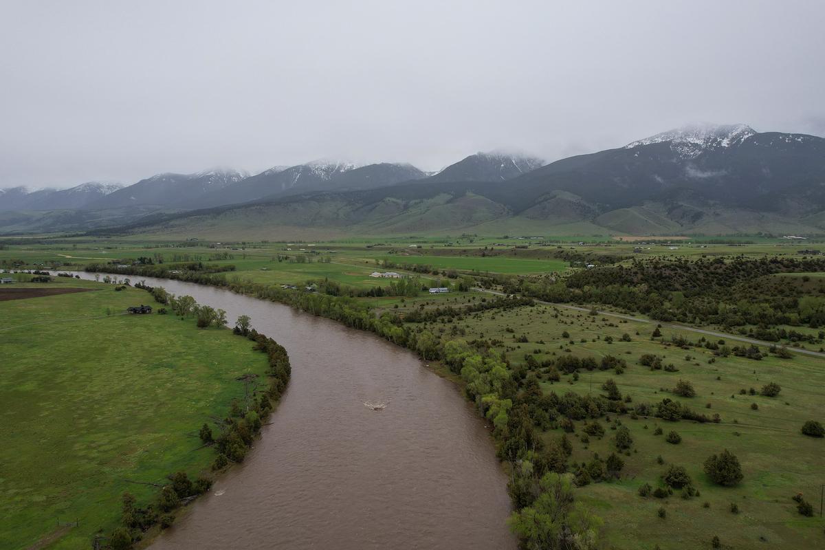 Breathtaking View of Yellowstone River in Paradise Valley, Montana - Snow-capped mountains, lush greenery, and meandering river under overcast sky.