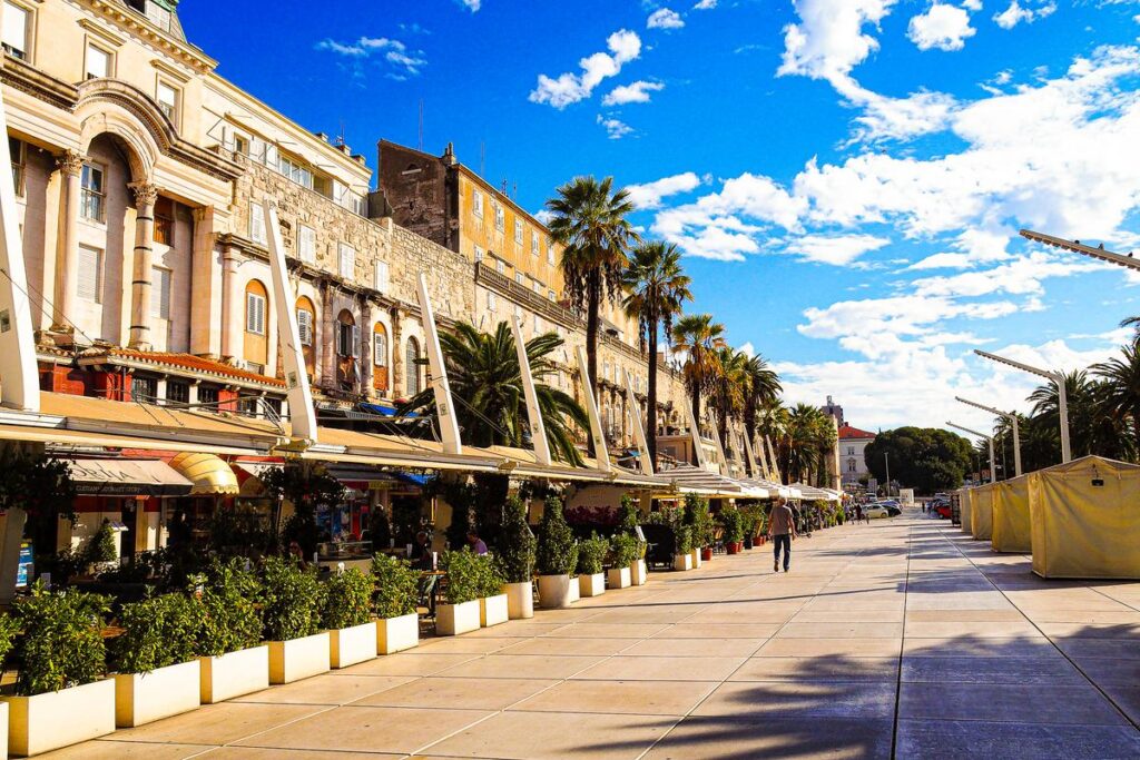 Bustling Day at the Historic Split Riva Promenade, Croatia: Vibrant coastal lifestyle scene with Mediterranean architecture, palm trees, and historic buildings.