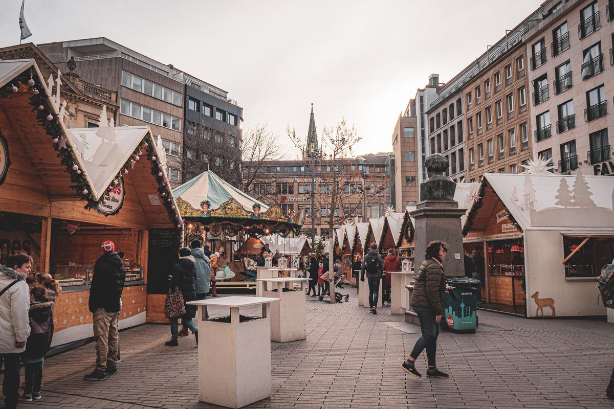 People strolling through a Christmas market in Düsseldorf with wooden chalets and seasonal decorations