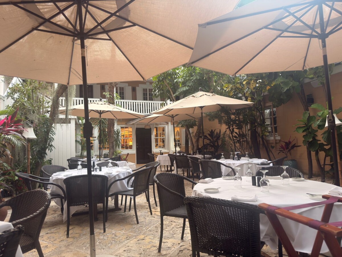 Umbrella-shaded courtyard tables set with white linens at Café Matisse in downtown Nassau
