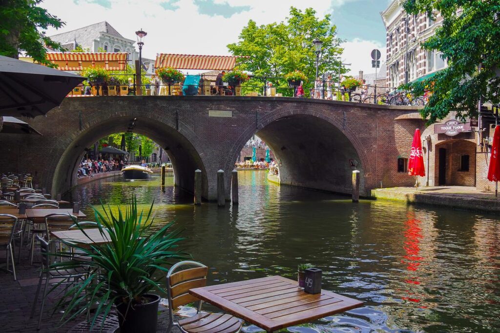 Canal-side dining along the Oudegracht in Utrecht, showcasing Dutch outdoor cafe culture, historic bridges, and picturesque waterfront views.