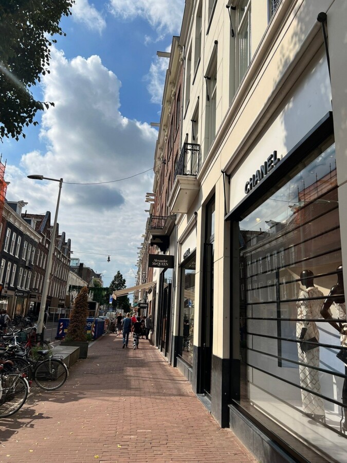 Shops in Amsterdam on a luxury street with Chanel boutique and historic facades.