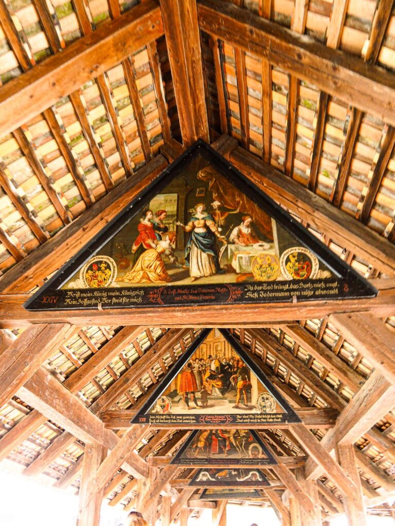Chapel Bridge (Kapellbrücke) in Lucerne, Switzerland, showcasing 17th-century roof paintings and rustic timber framing.