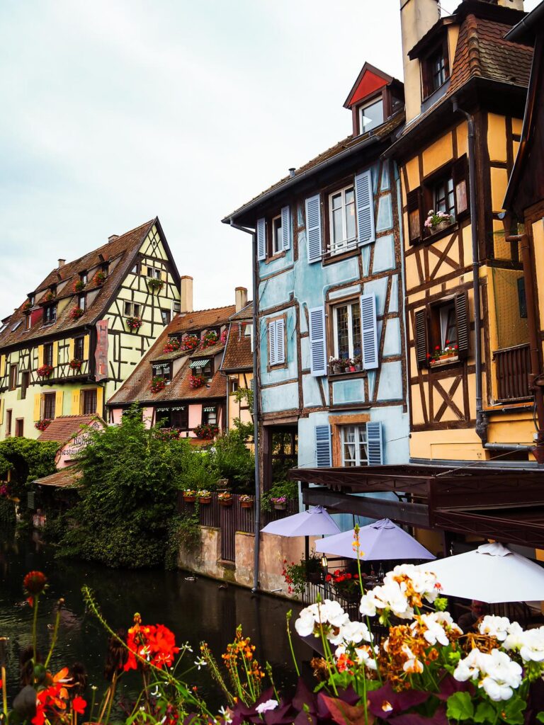 Charming canalside view of La Petite Venise in Colmar, France, with half-timbered buildings and florals