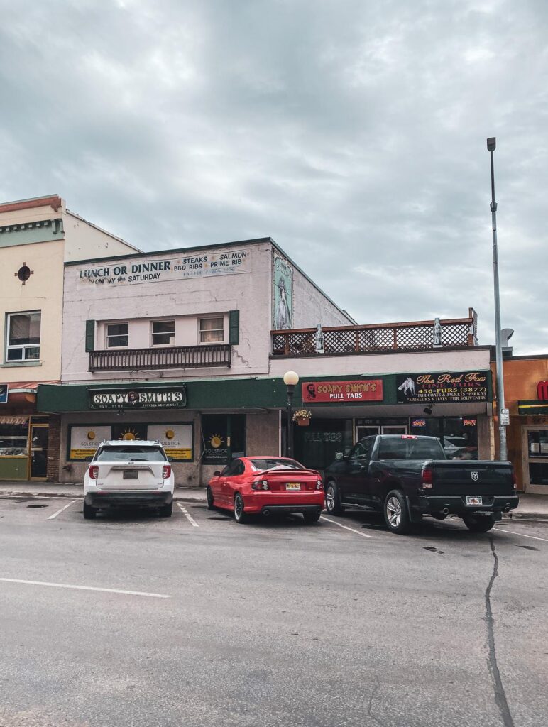 Charming Street Scene in Downtown Fairbanks, Alaska: Rustic architecture, parked vehicles, and overcast skies on Main Street.