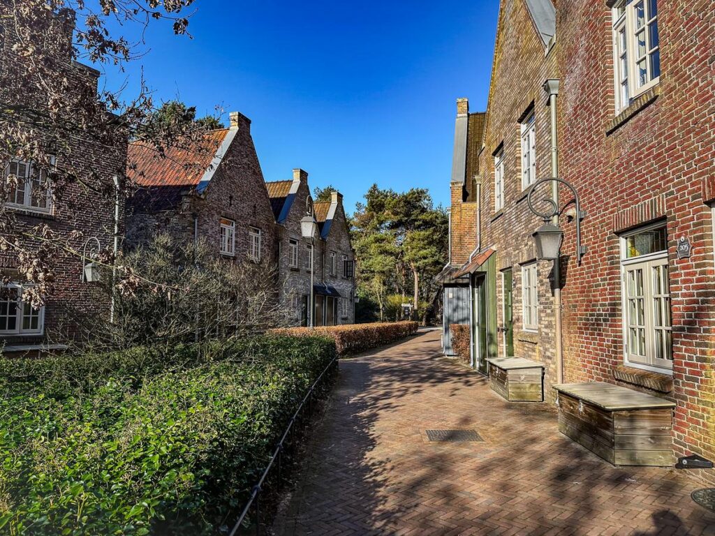 A sunlit cobblestone street lined with picturesque red brick village homes at Efteling Bosrijk resort.