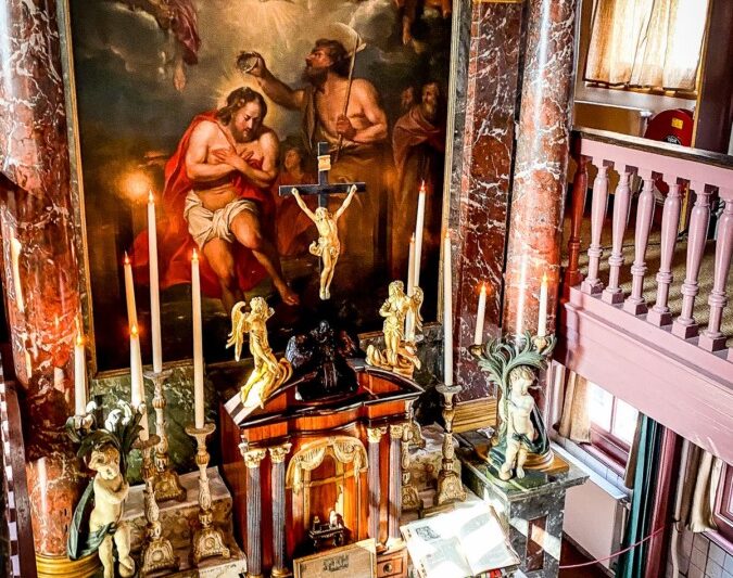 Clandestine 17th-century Catholic altar with ornate gold figures, dramatic religious painting, and atmospheric candle lighting.