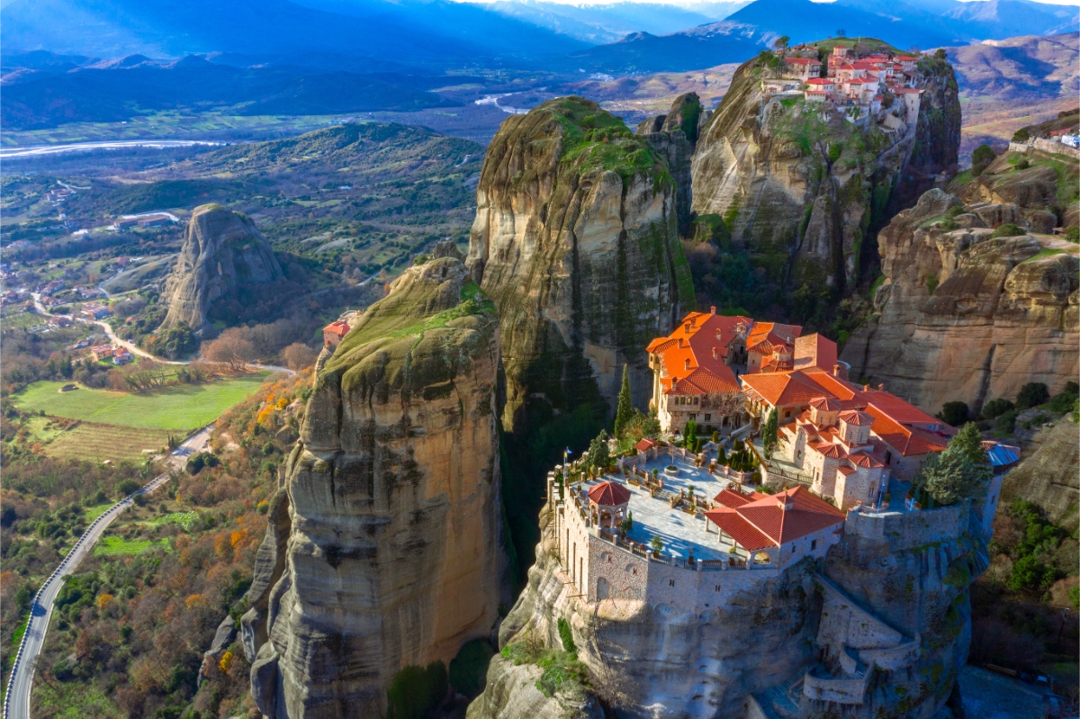 Cliffside village perched on sandstone pillars with terracotta roofs, terraces, and dramatic rock formations.