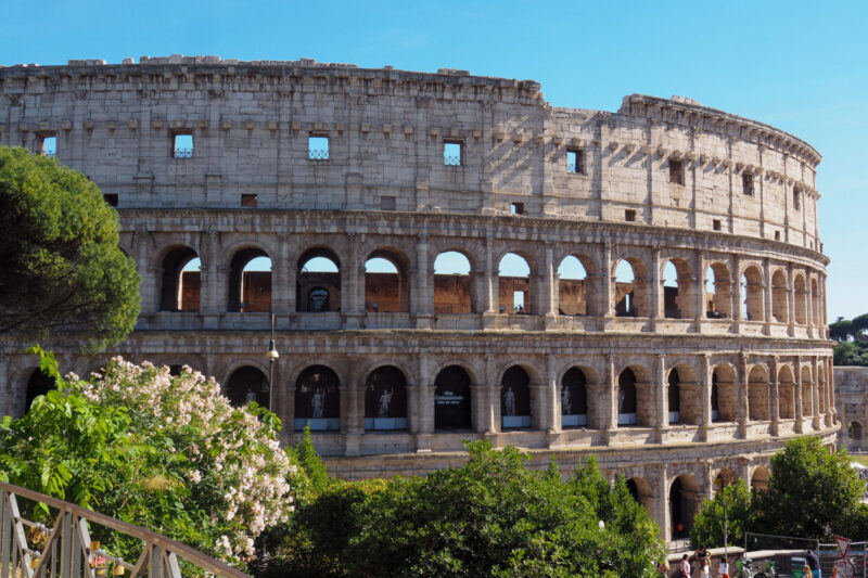 Colosseum in Rome, Italy under a clear blue sky framed by trees