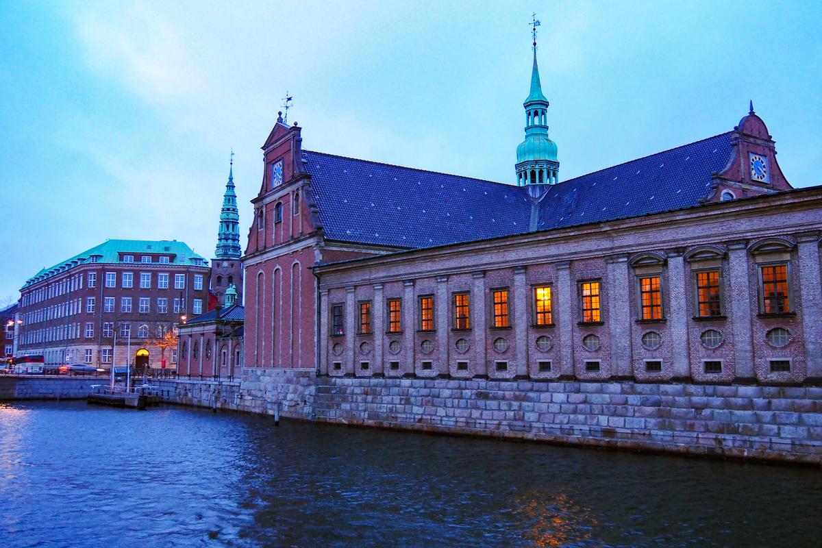Historic waterfront buildings in Copenhagen reflected in the harbor at dusk