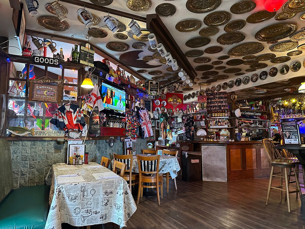 Cameron's Pub and Restaurant dining area packed with memorabilia, a plate-covered ceiling, and a warm bar scene in Half Moon Bay