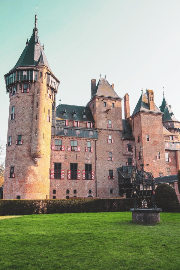 Red-brick towers and conical roofs of De Haar Castle under a blue sky