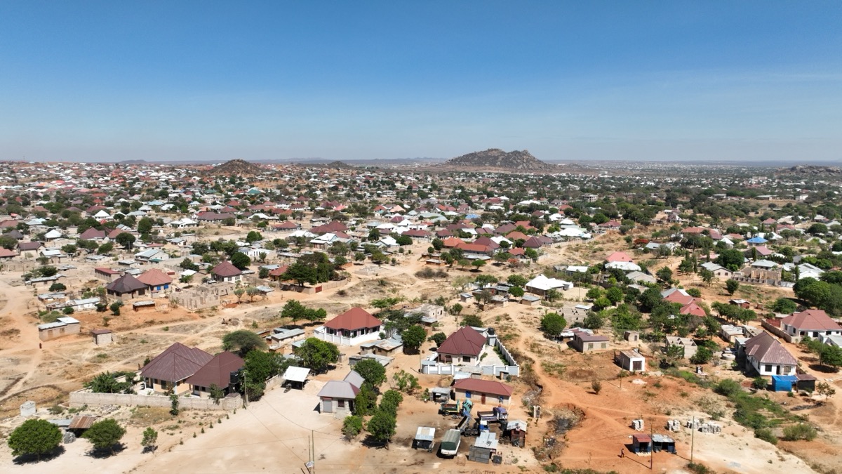 Aerial view of Dodoma city daytime showing low-rise residential houses, dusty streets, and surrounding hills.