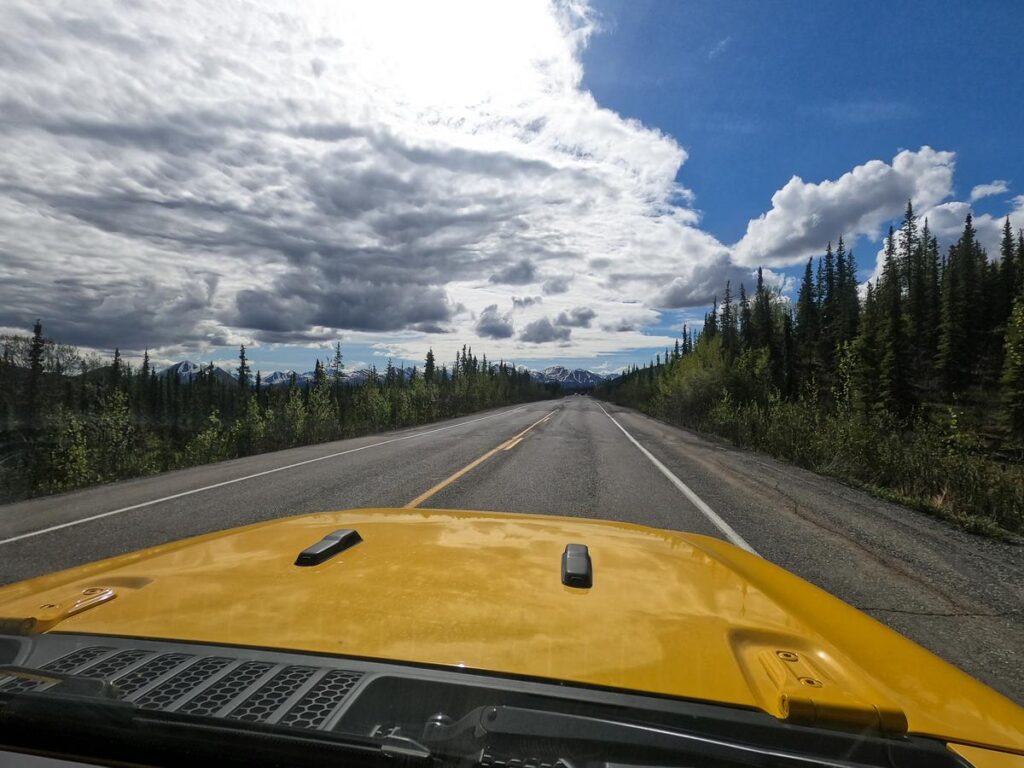 Driving Denali Park Road in a yellow Jeep, scenic Alaska adventure on Denali Highway