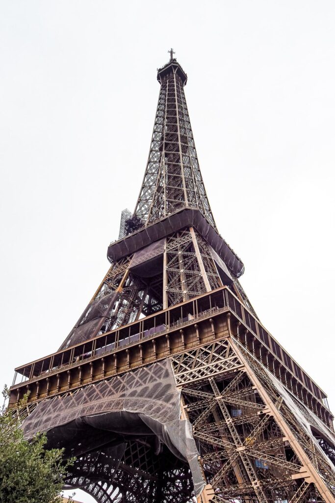 Ground-up perspective of the Eiffel Tower's intricate iron lattice work