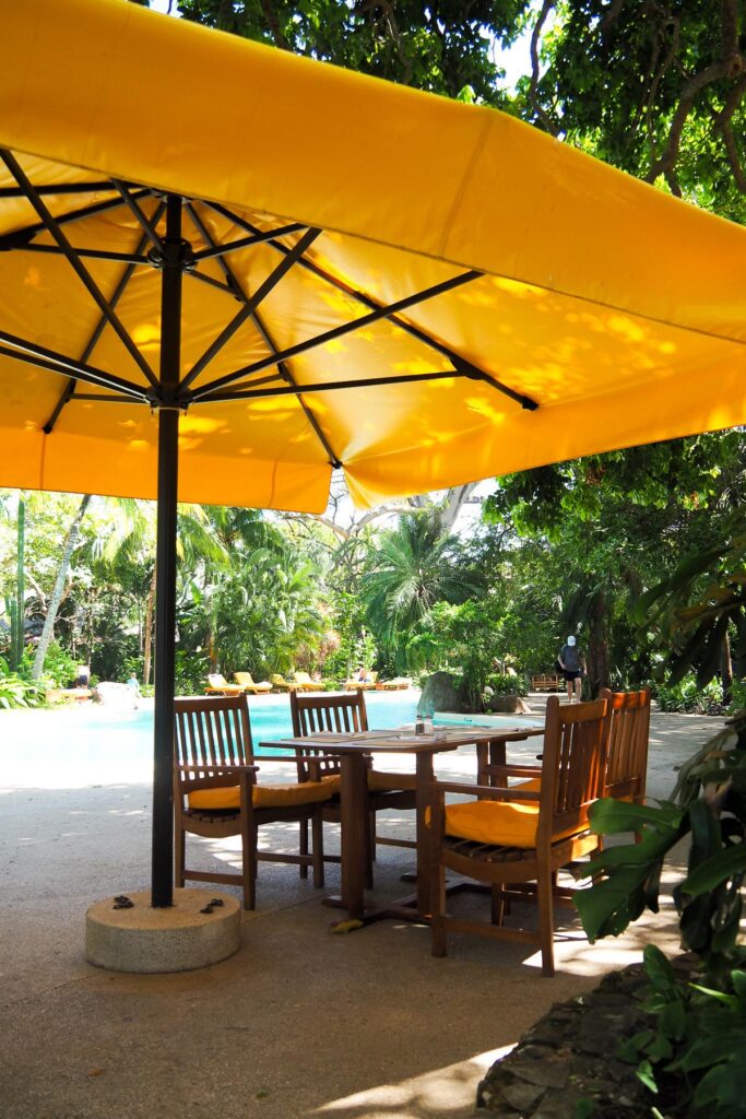 Idyllic poolside dining under yellow umbrella at El Capitan Suizo Hotel, Costa Rica