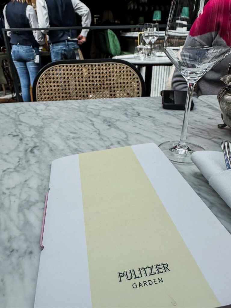 Elegant dining experience at Pulitzer Amsterdam Garden with stylish menu on marble tabletop.