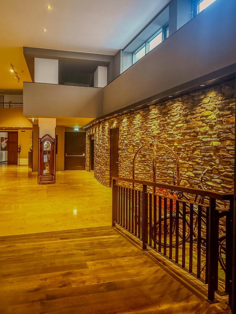 Interior view of Hotel Grauer Bär lobby with stone accent wall, wooden floors, and generous natural light creating a luxurious and welcoming atmosphere.