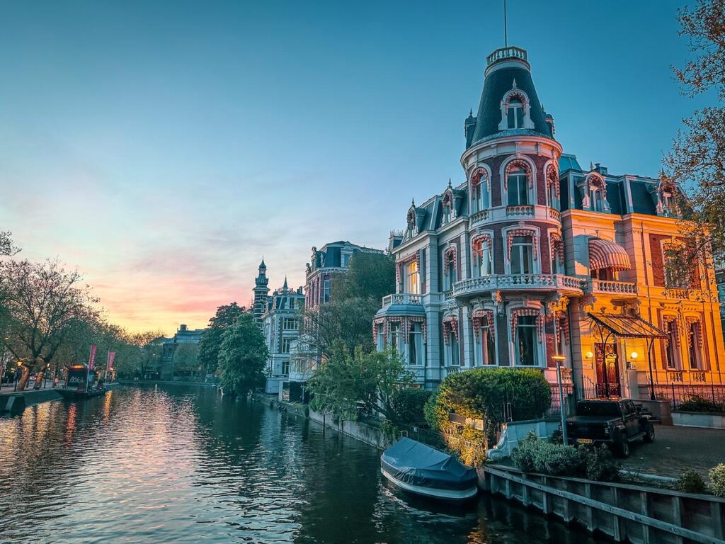 Enchanting Amsterdam sunset over historic canal with vibrant sky and tranquil waters.
