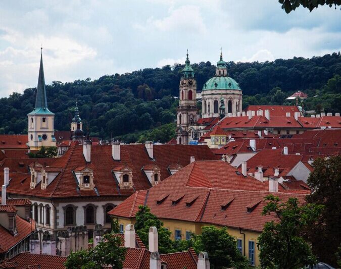 Enchanting view of Mala Strana's historic architecture amidst verdant foliage in Prague.