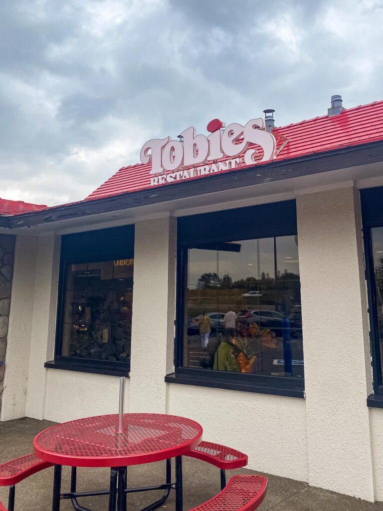 Exterior view of Tobies Restaurant in Hinckley, MN, featuring red patio table and inviting atmosphere.