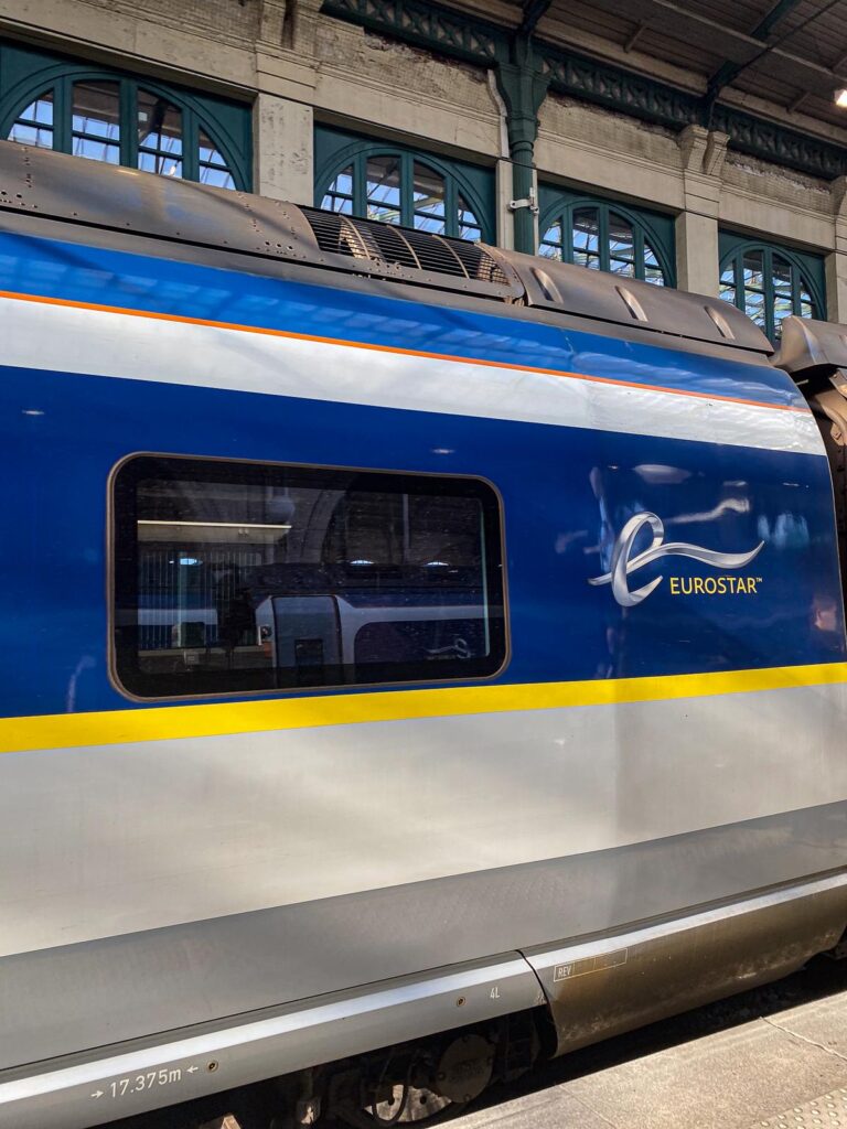 Eurostar train at Gare du Nord station in Paris, featuring blue and yellow livery with the Eurostar logo.