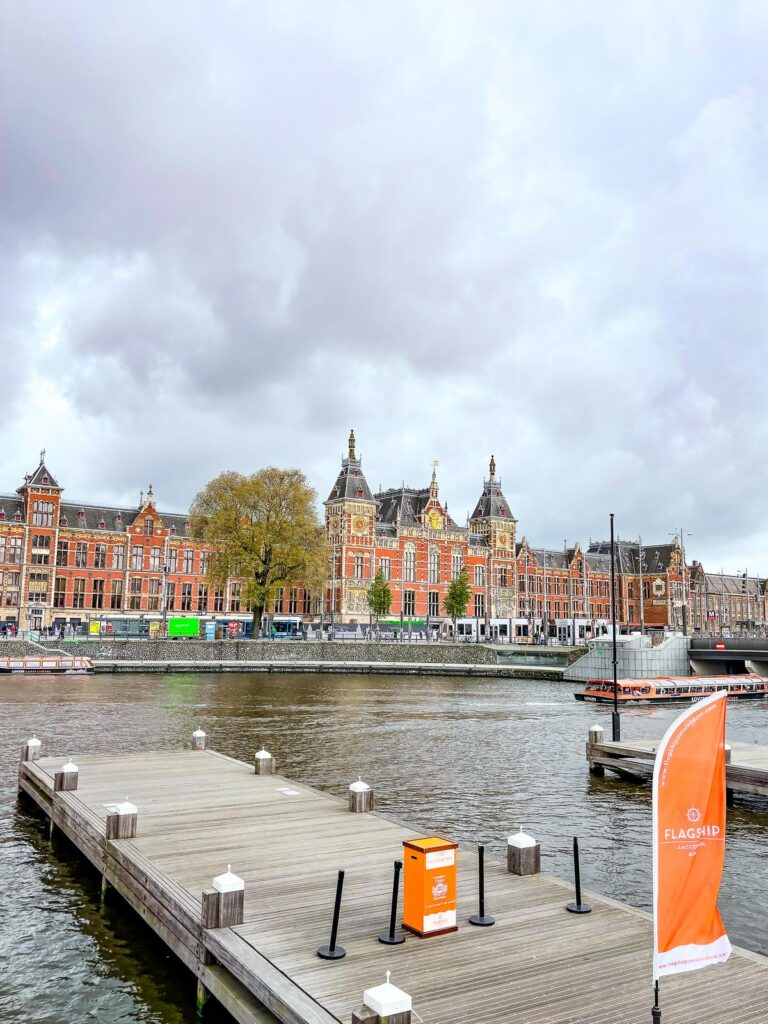 Explore Amsterdam Canals: Flagship Cruise Pickup by Centraal Station - Serene waterfront with Flagship banner.