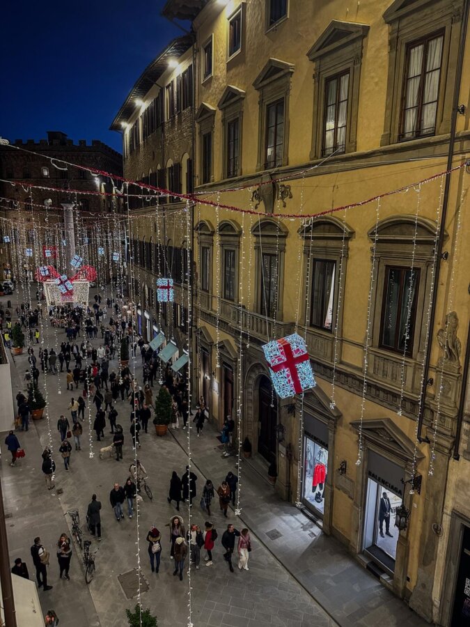Evening bustle on Florence street with festive lights viewed from Hotel Milu
