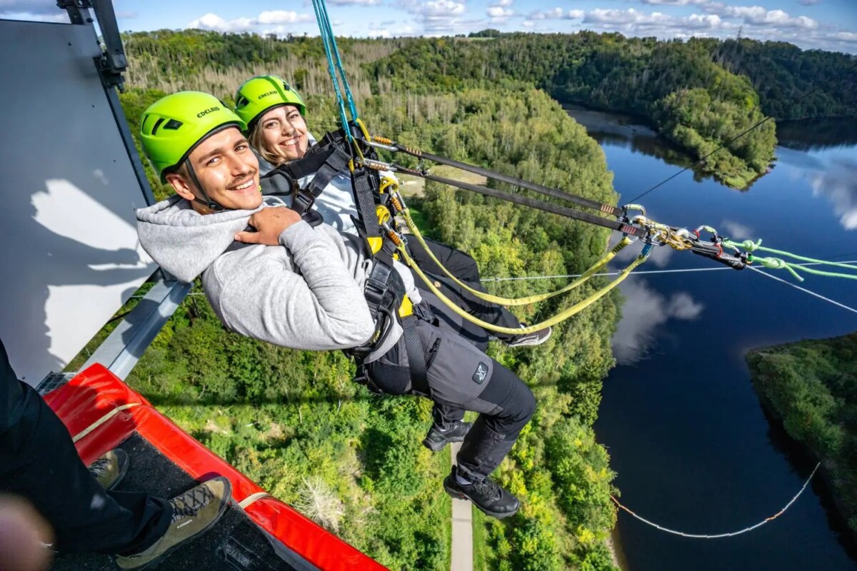Zip lines in Germany: tandem riders soar over forest river, best zipline Germany adventure.