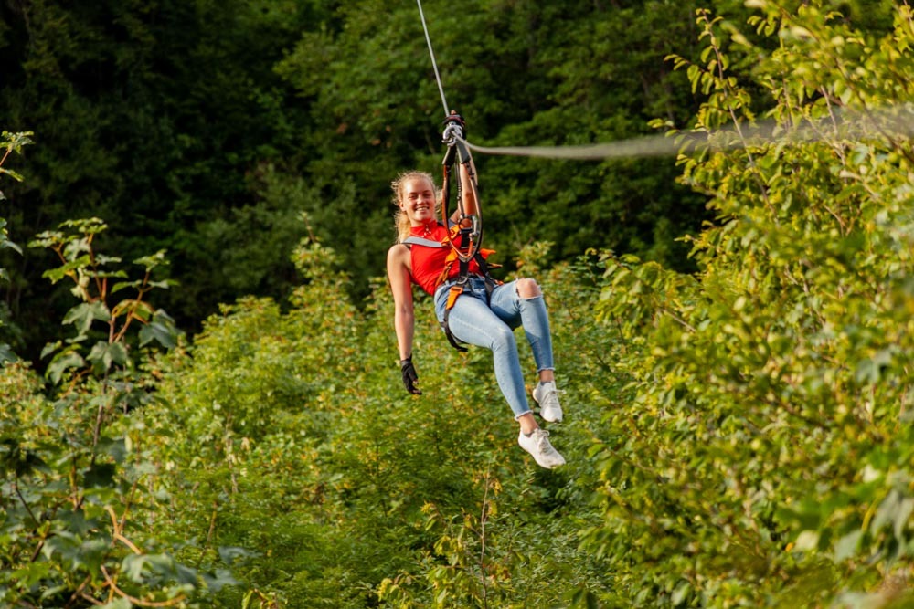 Woman enjoying one of the best zip lines in Germany through lush forest.