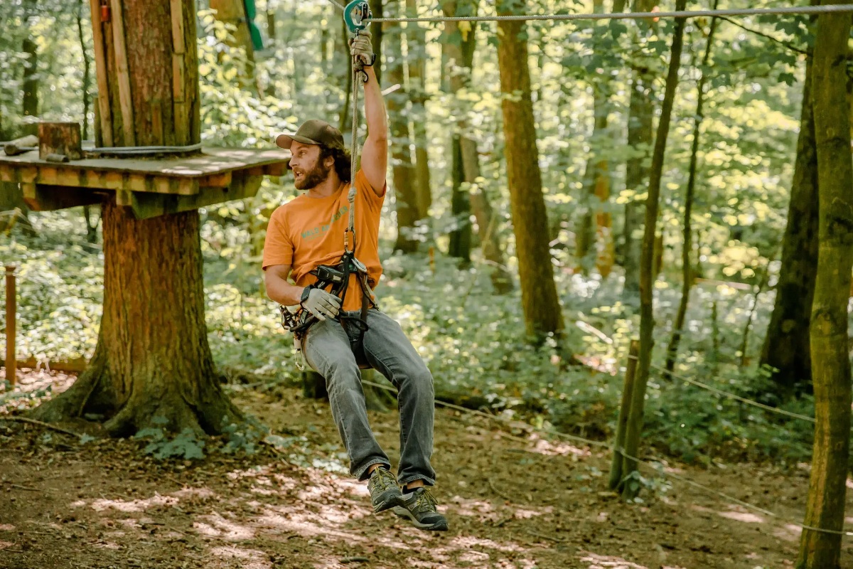 Man riding a zip line in Germany forest adventure park.