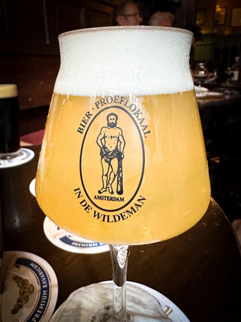 Close-up of frothy craft beer in a branded glass with the logo Bier Proeflokaal In de Wildeman Amsterdam in a traditional tasting room in Amsterdam.