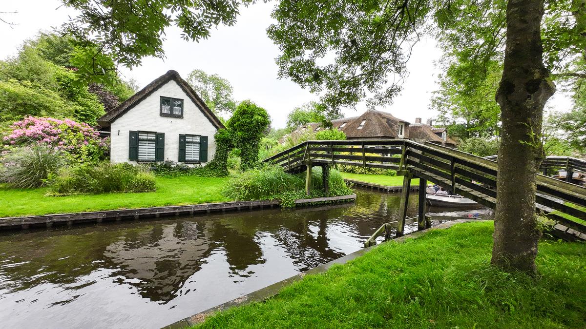 Idyllic Giethoorn Village, Netherlands with lush gardens, thatched-roof houses, and serene canals