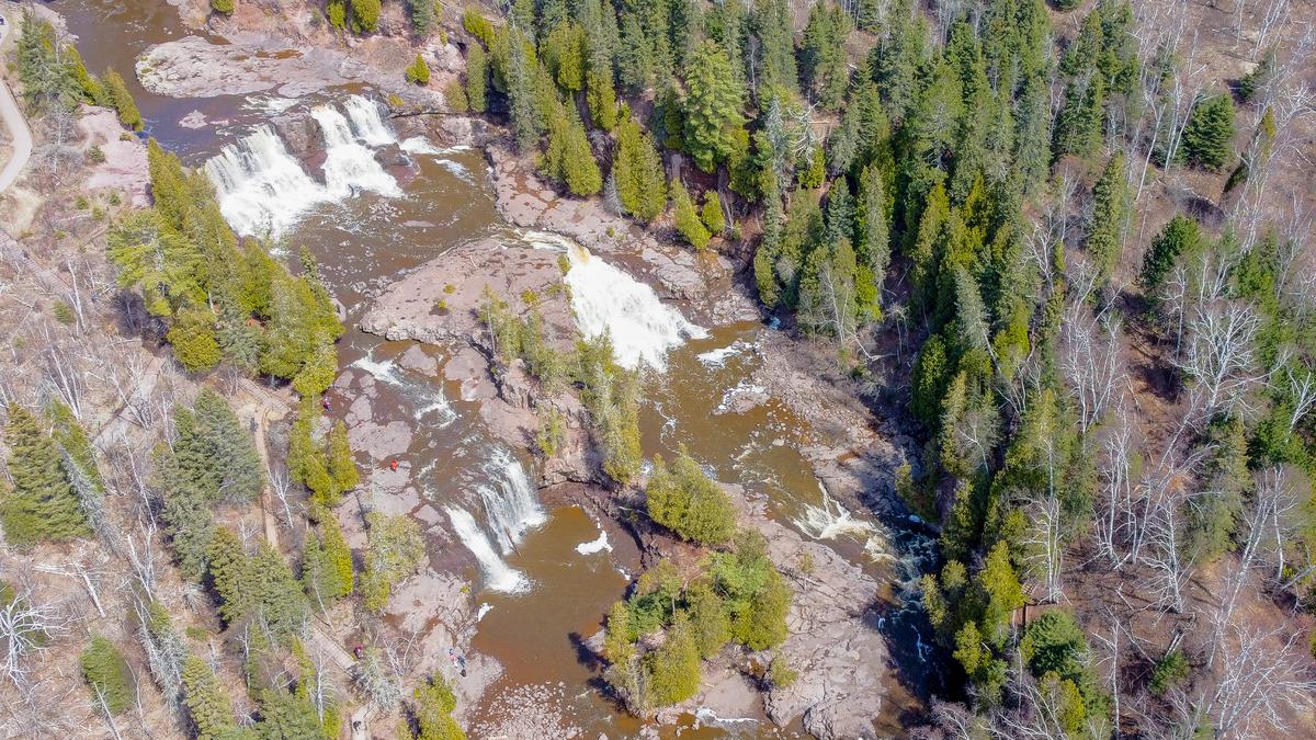Aerial photograph of Gooseberry Falls with cascading water, evergreen trees, and visitors at the park, illustrating Minnesota's scenic landscapes.