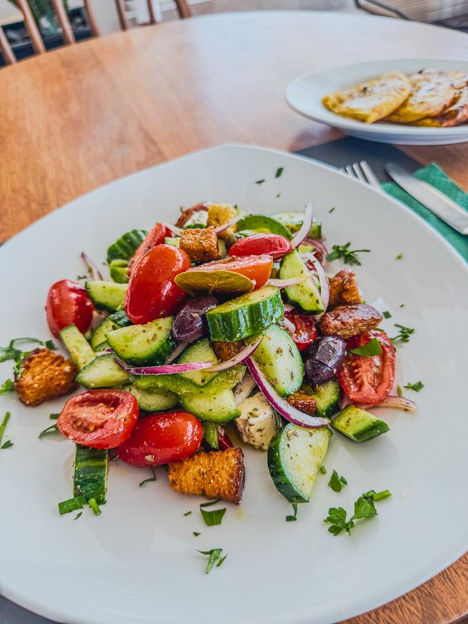 Colorful Greek salad with Santorini seascape view, ideal for travel enthusiasts in Greece