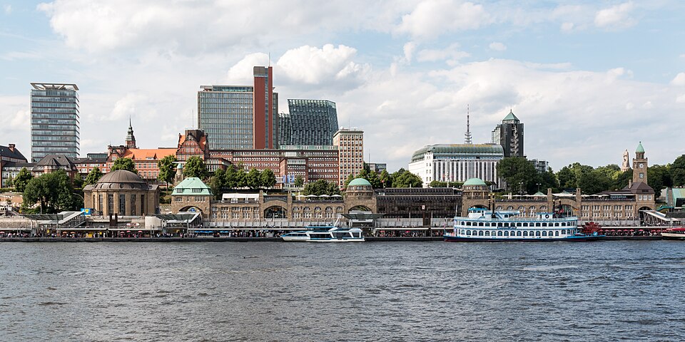 Hamburg waterfront cityscape with landmarks, monuments, boats, and historic harbor buildings.