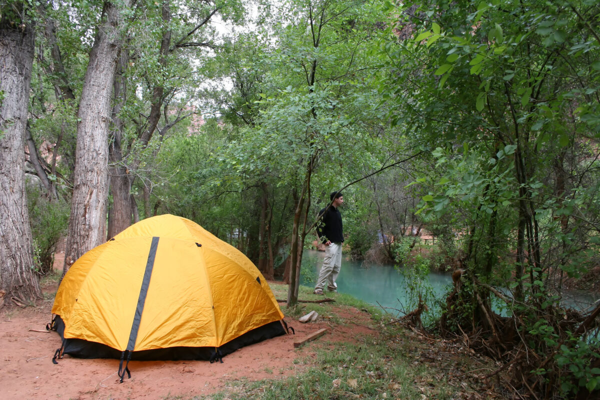 Havasu Falls Campground with yellow tent beside turquoise pool on Havasupai Indian Reservation, Arizona.